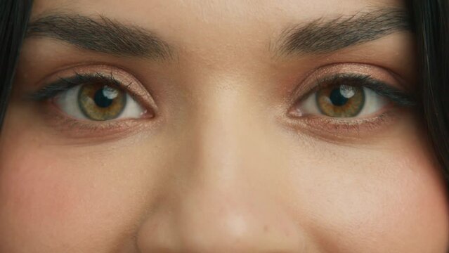 Zoom in macro hazelnut green eyes of young beautiful woman. Slow motion hazelnut brown eyeball iris. Good vision, I see you, the eye is the mirror to one's soul concept. Latino girl looking at camera