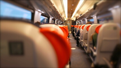 Interior of highspeed train transportation seen from the back perspective with passengers traveling
