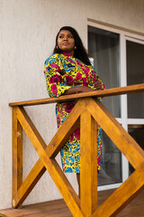 African american woman relaxing and enjoying sun while standing at terrace or balcony at sunlight at summer. Slow living and tranquil moment and mental health. Backyard terrace vacation weekend