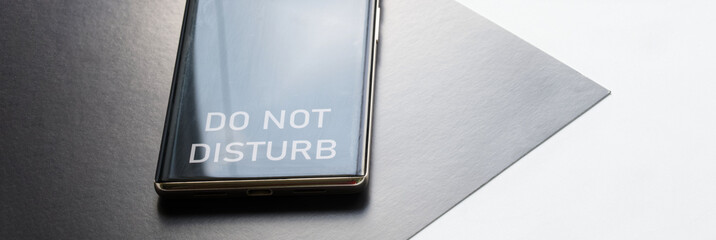 Modern smartphone with the inscription «do not disturb» on a two-tone black and white background....
