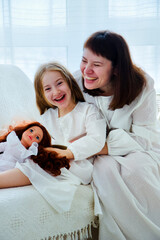 Portrait of happy family. Young mother and little daughter sits in pajamas on a couch and having fun together at home.