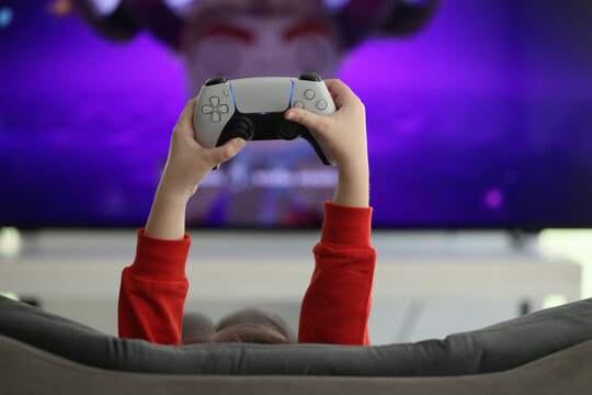 Hands of little girl holding game console against screen