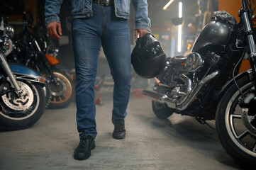 Fototapeta na wymiar Cropped shot of biker carrying helmet standing over motorcycle row in garage