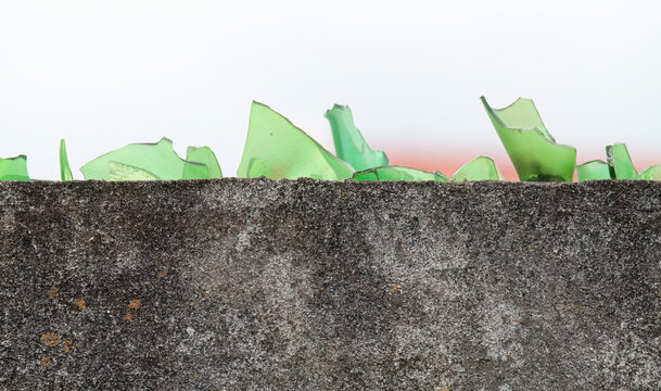 Pieces of broken glass on the top of a concrete wall
