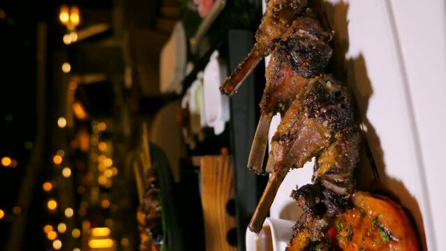 Roasted grilled lamb chops with a luxury fine dining backdrop. Juicy spare ribs with spices and sauce. A tasty lunch or dinner option at a high-end restaurant. Vertical video 