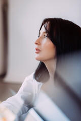 The brunette sits thoughtfully near the white wall 4527.