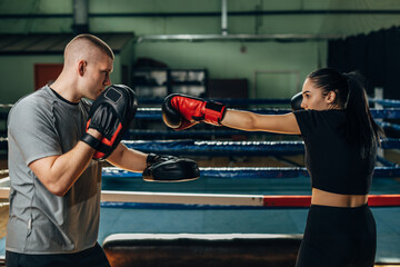 A Caucasian woman practices punching with her coach