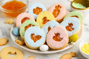 Easter Linzer cookies in the shape of eggs filled with apricot jam and sprinkled with colored powdered sugar. Festive dessert. Selective focus