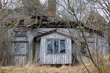 Old derelict farm house abandoned. Broken windows and roof with vegetation