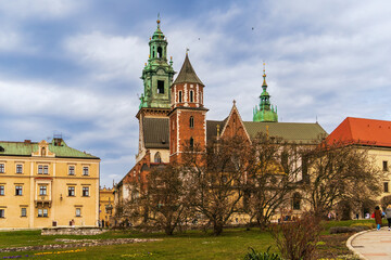 Obraz premium Historical Wawel Royal Castle in Krakow, Poland on a cloudy spring day against a cloudy sky, magnolia with white unopened flowers in the foreground, European historical landmarks, European cities