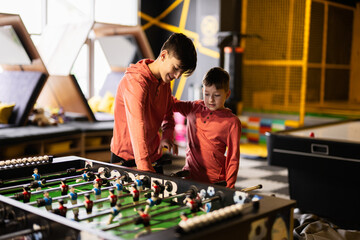 Brothers playing table football in kids play center.