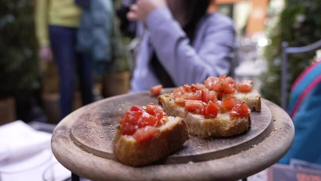 Italian Appetizer Bruschetta on Wooden Plate at restaurant. Bread and tomatoes