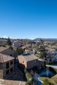 Imagen del pequeño pueblo madrileño de Buitrago de Lozoya con sus casas y la verde montaña al fondo bajo un cielo soleado.