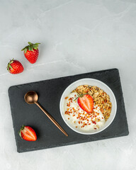 A bowl of granola with yogurt, strawberries and freeze-dried berries. The concept of proper nutrition, homemade food, Light background, top view.
