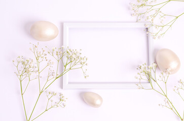Easter mother-of-pearl eggs and hepsophila flowers around a frame on a white background