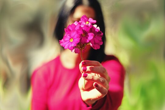 Mujer sosteniendo una flor fucsia en primer plano