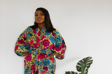 Young african american woman wearing dress posing over white wall at home - inclusion and diversity...