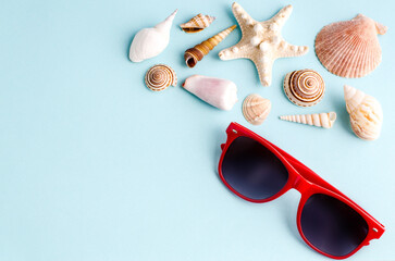 Seashells and sunglasses on a blue background with space for text