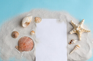Seashells, sand and a blank sheet of paper on a blue background with space for text.
