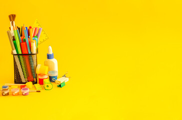 Different office supplies in a cup on a yellow background with a place for text.