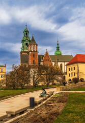 Fototapeta na wymiar Historic Wawel Royal Castle in Krakow, Poland, on a spring day against a cloudy sky, magnolia trees with white flowers in the foreground, a tourist on a bench, traveling in European cities