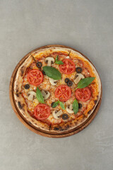 Pizza margherita with tomatoes and mushrooms on a gray background, top view