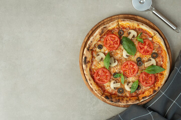 Pizza margherita with tomatoes and mushrooms on a gray background, top view