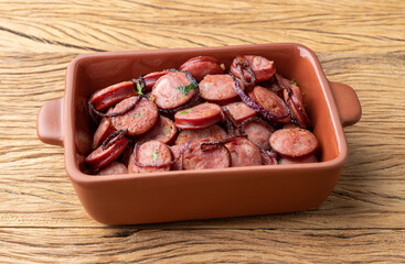Grilled calabrese sausage portion with onion over wooden table
