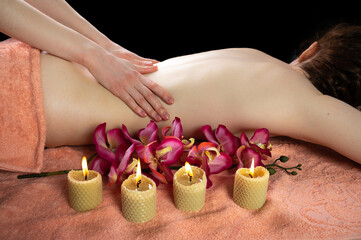 bare back of a girl in a spa salon with a towel and candles. concept of body care, relaxation and stress relief