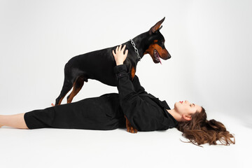 A young beautiful Doberman with a chain around his neck and his owner, elegant girl in a long black coat and bright red lipstick. Isolated on a white background. - Powered by Adobe