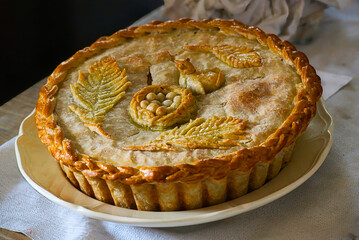 A beautifully decorated pie crust with leaves, a bird, eggs and nest.