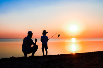 Fototapeta na wymiar A Happy father and child fishermen catch fish by the sea on nature silhouette travel