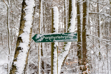 A snow-covered sign of the porphyry educational trail on the Rochlitzer Berg