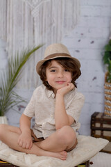 Boy wearing a hat making faces with a brick wall and neutral clothes 