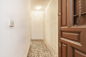 Entrance hall of a house with a long hallway with white painted walls and terrazzo flooring with black dots