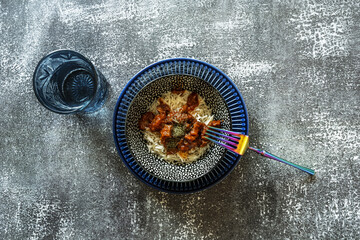 A bowl of rice with squid in American sauce and an iridescent metal fork