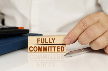 In the hands of a businessman, wooden blocks with the inscription - Fully Committed