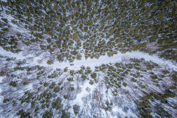 Flight over the winter mountains with road serpentine and pine forest. Top down view. Landscape photography