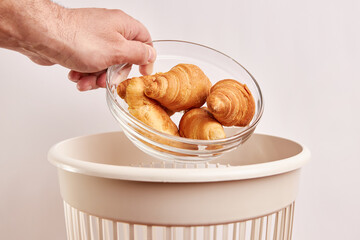 Expired, stale croissants are thrown into the trash. Disposal and recycling of food products.