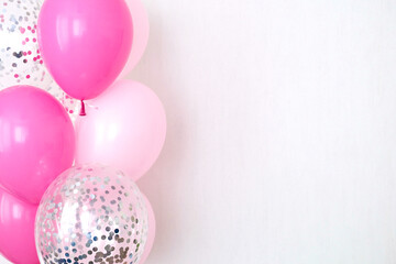 A bundle of pink and transparent air balloons with silver confetti, copy space for your text,...