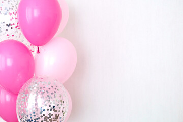 A bundle of pink and transparent air balloons with silver confetti, copy space for your text, tender pastel colors for a girlish party