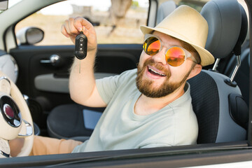 Naklejka premium Handsome happy man showing key of new car - Rental and buy new car concept