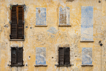 Fototapeta na wymiar Old facade with windows and shutters but also painted on not real windows.