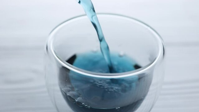 Pea tea "Blue Butterfly" from the flowers of the Clitoris close-up is poured into a transparent glass. Wellness and detoxification