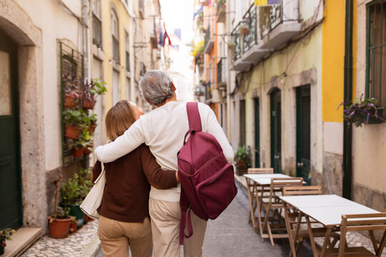 Senior Couple Hugging Walking On Lisbon Street Outdoors, Back View