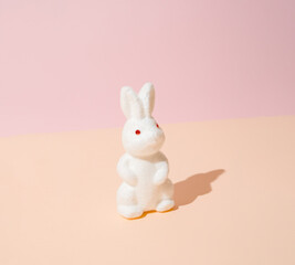 White Easter bunny on a light yellow and pink pastel background.