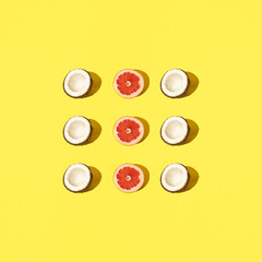 Half coconut and grapefruit on a pastel background. Background yellow color.