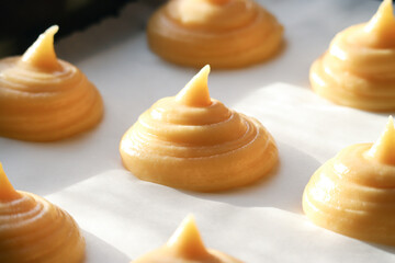 Close up of uncooked French choux pastry dough in a baking tray with sunlight and shadow. It's a...