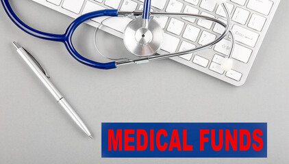 MEDICAL FUNDS word with Stethoscope on keyboard on grey background