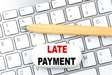 LATE PAYMENT text on eraser with pencil on keyboard